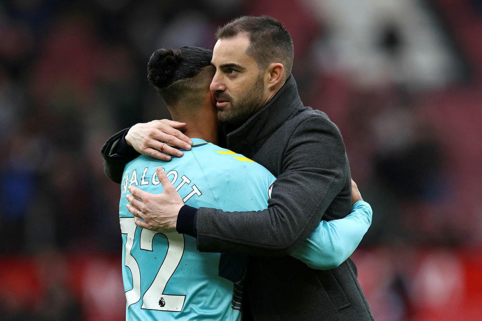 Rubén Sellés faðmar Theo Walcott eftir leikinn á Old Trafford …
