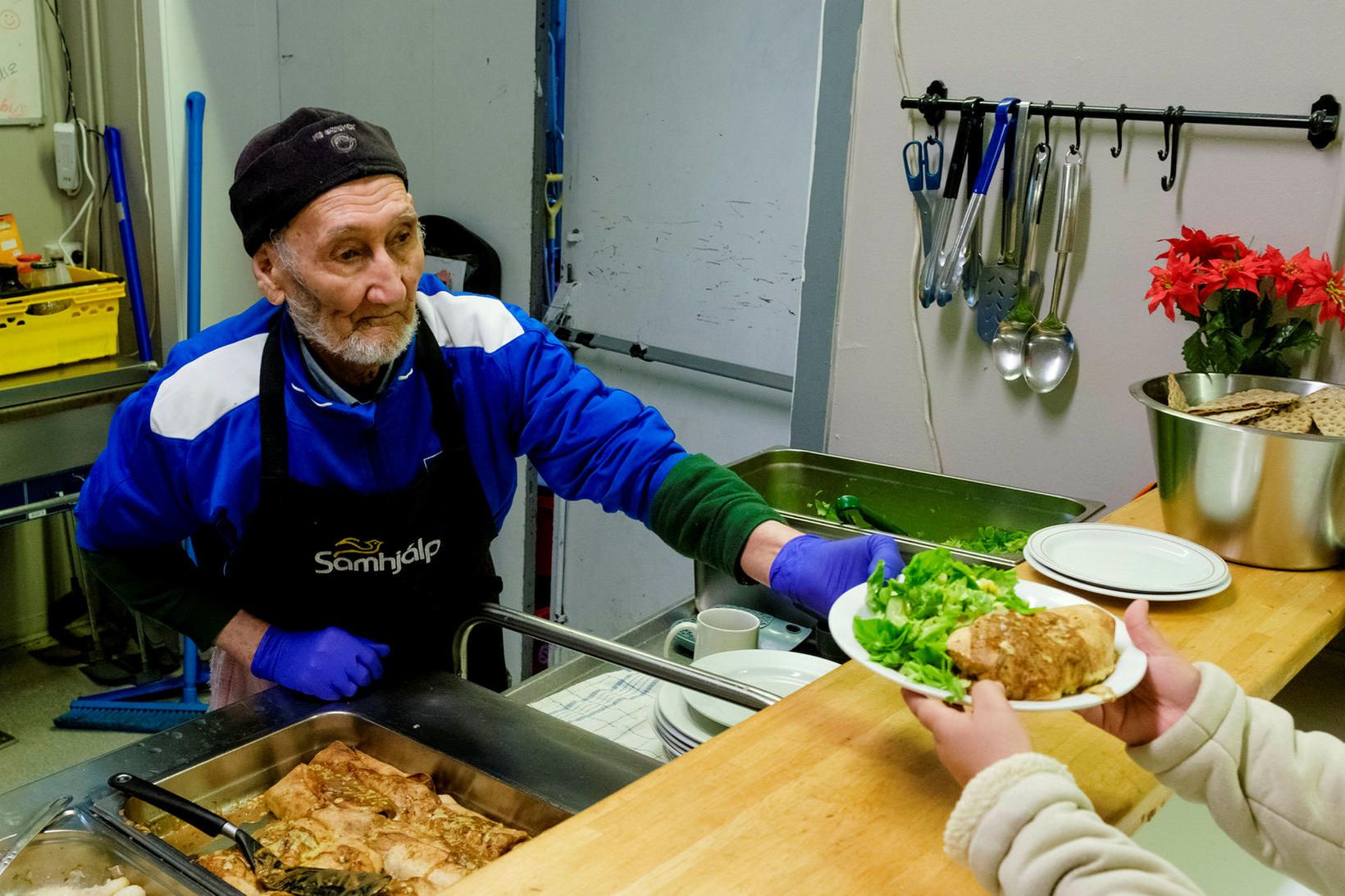 Starfsfólk í óða önn að afgreiða mat í kaffistöðu Samhjálpar.