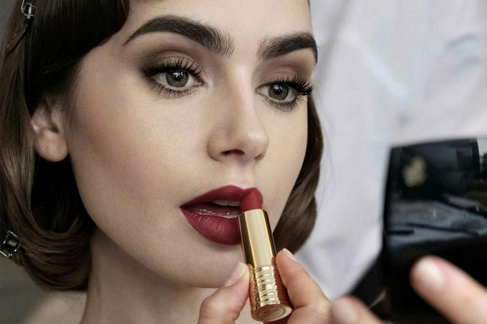 Lily Collins setur á sig varalit. Um er að ræða …